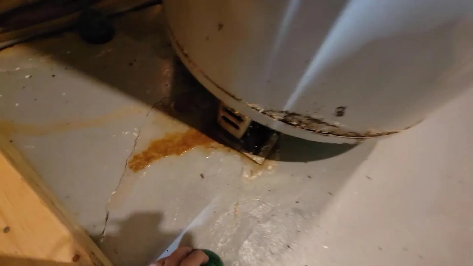 Rust-colored staining on a floor beneath the base of a water heater tank